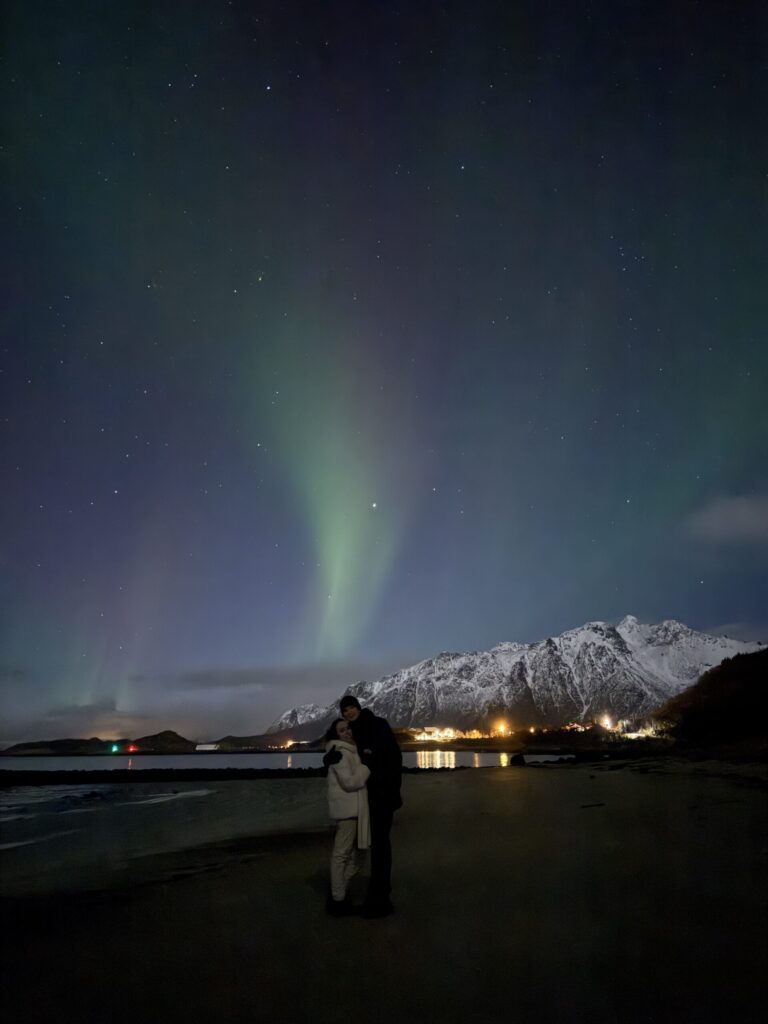 Travellers watching the northern lights on an Arctic beach in Norway